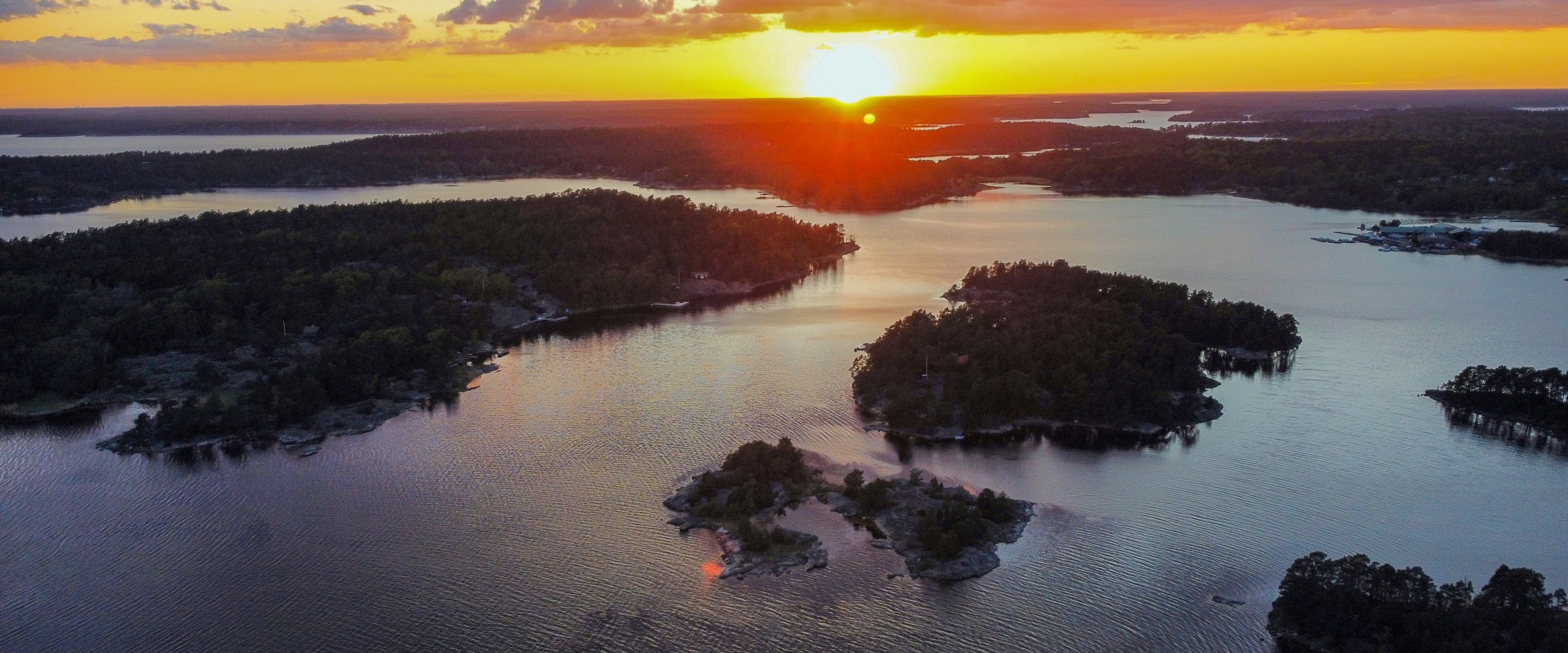Sunset over a scenic archipelago with scattered islands and calm waters.